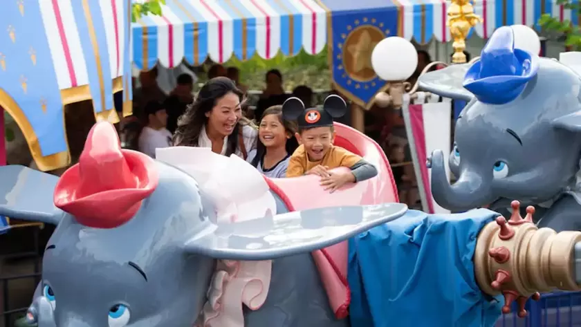 Семейные развлечения: Женщина с детьми наслаждается аттракционом Dumbo в Disneyland