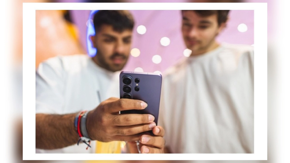 Deux jeunes hommes examinent le dos d'un smartphone Samsung Galaxy